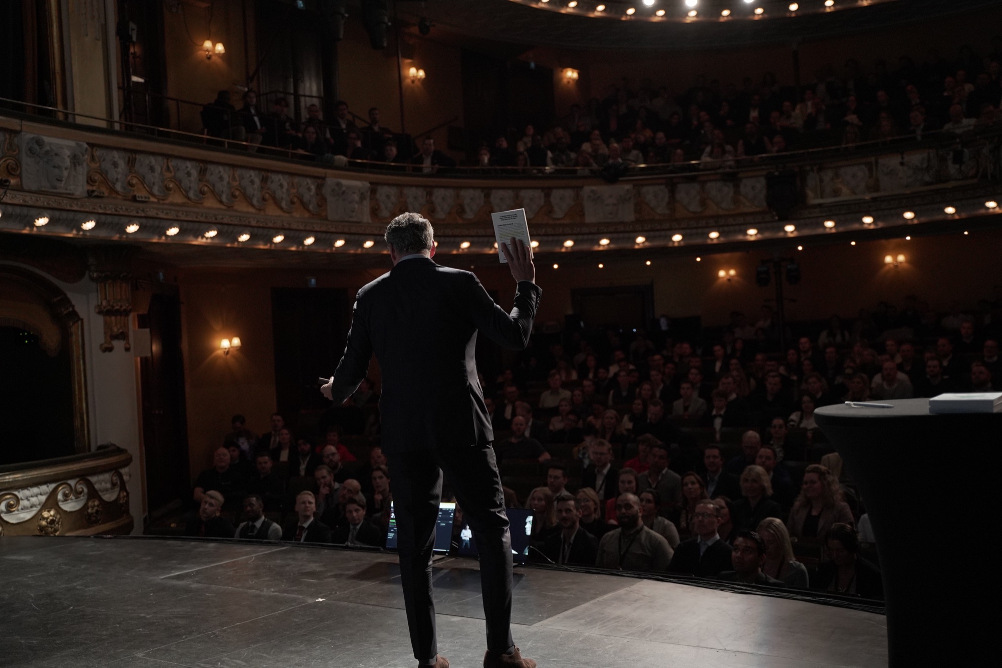 Oliver talar inför en publik i en teater